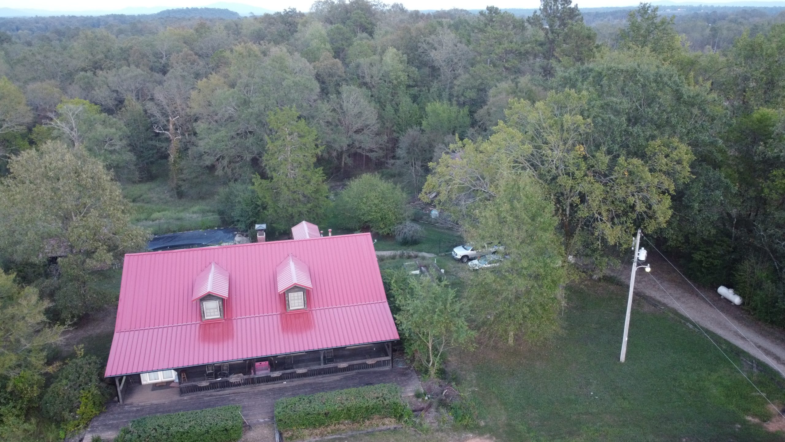 Aerial view of a residential metal roof in a wooded area of Central Arkansas.